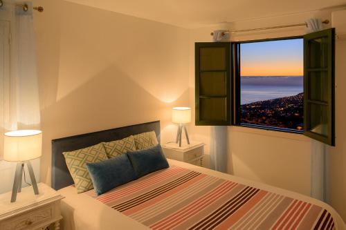 ein Schlafzimmer mit einem Bett und einem großen Fenster in der Unterkunft Recanto das Florenças (1) in Arco da Calheta