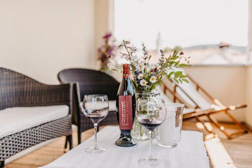 a table with two glasses and a bottle of wine at Casa Krasna Gourmet Boutique Hotel in Lokev