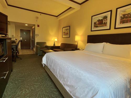 a hotel room with a large bed and a living room at Holiday Inn Express Hotel & Suites Charleston-Ashley Phosphate by IHG in Charleston