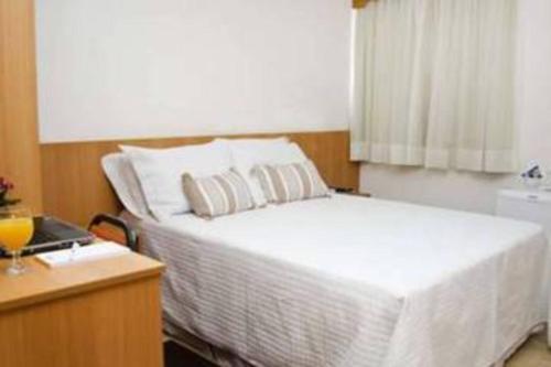 a bedroom with a white bed and a window at Millian Hotel in Jundiaí