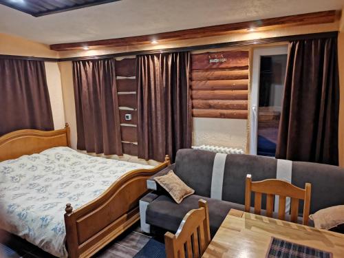 ein Schlafzimmer mit einem Bett, einem Sofa und einem Tisch in der Unterkunft Apartments Artic in Jahorina