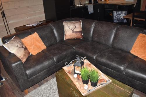 a brown leather couch with pillows and plants on a table at Norbel Hytte Norway in Vradal