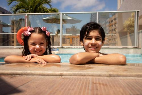 two young girls laying in a swimming pool at Hilton Garden Inn Maceio in Maceió