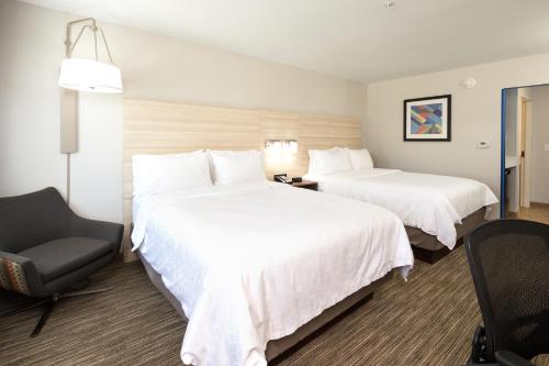 a hotel room with two beds and a chair at Holiday Inn Express & Suites - Michigan City by IHG in Michigan City