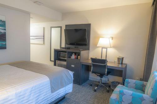 a hotel room with a bed and a desk with a television at Best Western Plus Sands in Vancouver