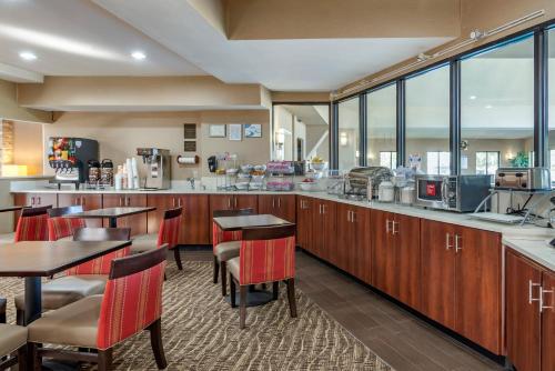 a restaurant with wooden cabinets and tables and windows at Comfort Suites near Robins Air Force Base in Warner Robins