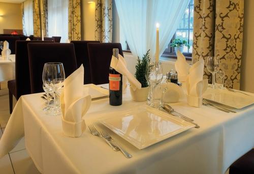 a white table with a bottle of wine on it at Hotel Camelot in Szczawno-Zdrój