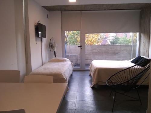 a room with two beds and a table and a window at Pueyrredon 1101 in Rosario