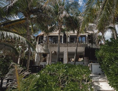 a house with palm trees in front of it at NEST Tulum in Tulum