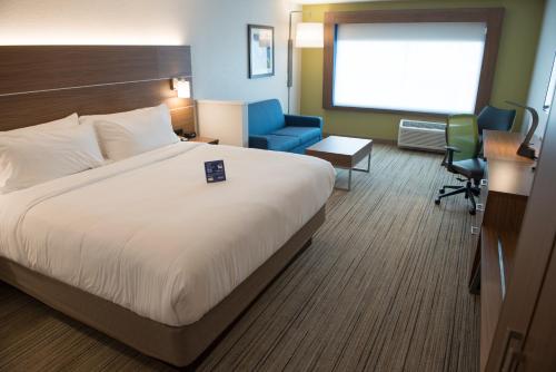 a hotel room with a large bed and a blue chair at Holiday Inn Express & Suites - Mishawaka - South Bend by IHG in Granger