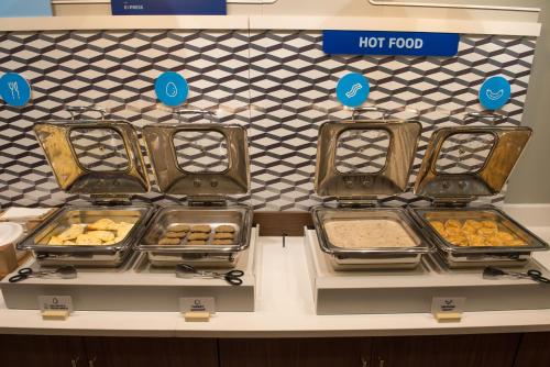 a counter with trays of food on display in a store at Holiday Inn Express & Suites - Mishawaka - South Bend by IHG in Granger
