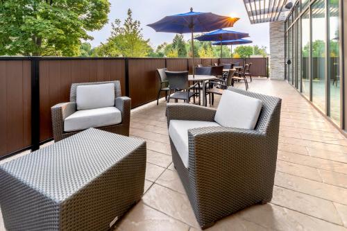 a patio with chairs and tables and umbrellas at Holiday Inn Express & Suites - Milwaukee West Allis by IHG in West Allis