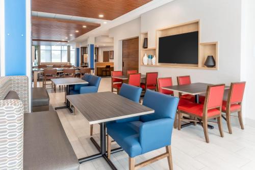 a restaurant with tables and chairs and a flat screen tv at Holiday Inn Express & Suites - Milwaukee West Allis by IHG in West Allis