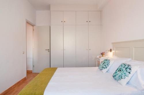 Flatguest Triana في لاس بالماس دي غران كاناريا: غرفة نوم بيضاء مع سرير كبير مع دواليب بيضاء