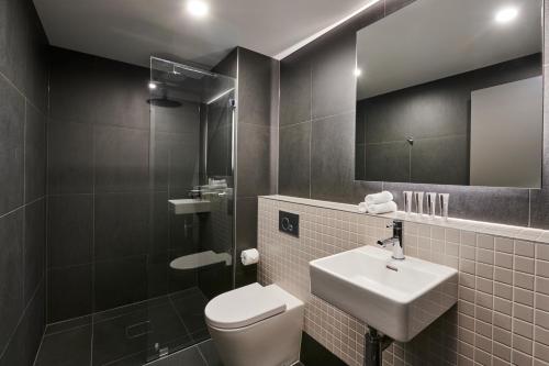 a bathroom with a toilet and a sink and a mirror at Abode Belconnen in Canberra