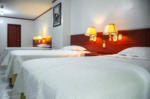 a hotel room with two beds with white sheets at REGAL HOTEL in Machala