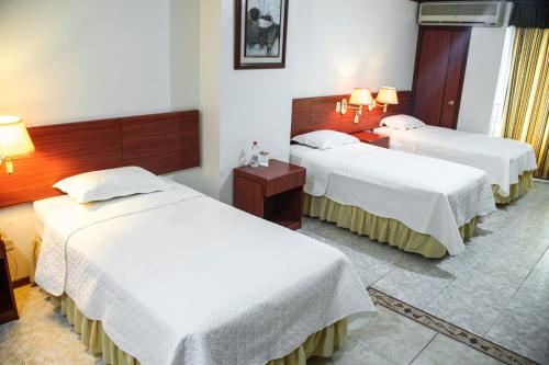 a hotel room with two beds with white sheets at REGAL HOTEL in Machala
