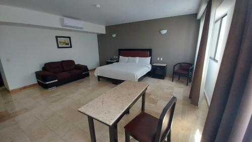 a hotel room with a bed and a table and a couch at Imperio de Angeles Executive León Poliforum in León