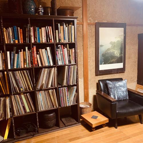 a book shelf filled with books next to a chair at Ensoh in Okayama