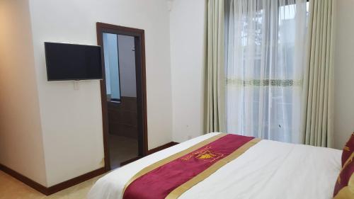 a bedroom with a bed and a tv and a window at Khách Sạn Cây Thông in Tam Ðảo