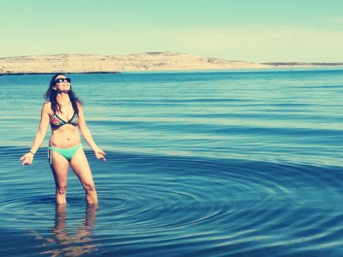 Una mujer en bikini parada en el agua en El Canto de la Ballena en Puerto Pirámides