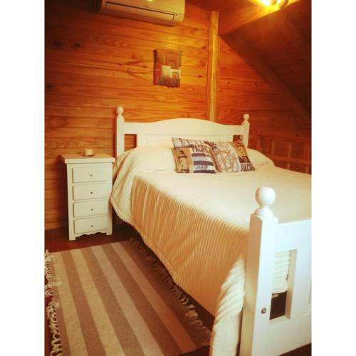 a bedroom with a white bed and a wooden wall at El Canto de la Ballena Bungalow 2 niveles in Puerto Pirámides