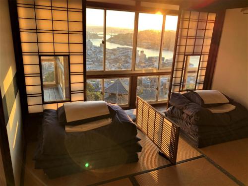 a room with two beds and a large window at Onomichi Guest House Miharashi-tei in Onomichi