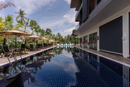 a swimming pool with chairs and umbrellas next to a building at Roxy Sematan & Telok Serabang in Sematan