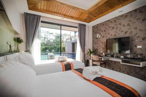 a hotel room with two beds and a television at The Rabbit Home in Nakhon Nayok
