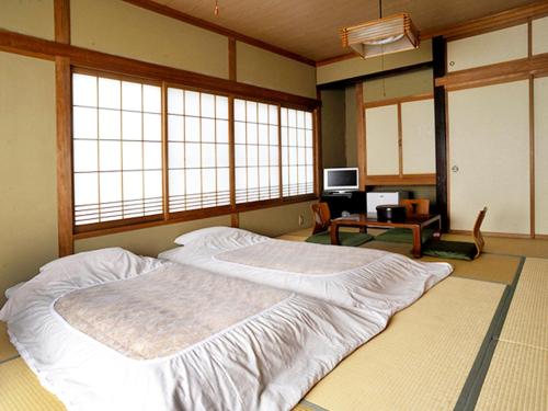 a bedroom with a large bed in a room with windows at Ryokan Seifuso in Matsumoto