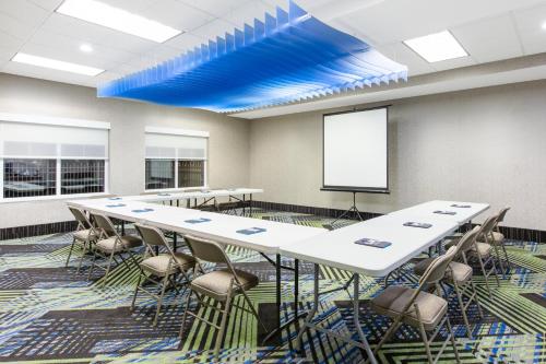 a conference room with tables and chairs and a screen at Holiday Inn Express Hotel & Suites Seaside Convention Center by IHG in Seaside