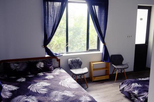 a bedroom with a bed and two chairs and a window at Moc Chau Cottage homestay in Mộc Châu