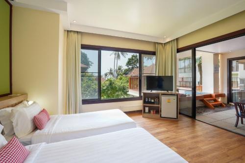 a hotel room with two beds and a flat screen tv at The Briza Beach Resort, Samui - SHA Plus in Chaweng