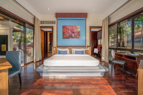 a bedroom with a bed and a desk and windows at The Briza Beach Resort, Samui - SHA Plus in Chaweng
