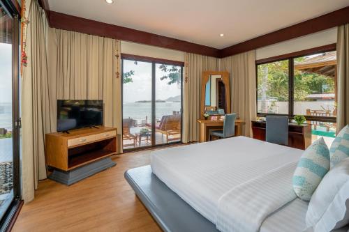 a bedroom with a bed and a television and a balcony at The Briza Beach Resort, Samui - SHA Plus in Chaweng
