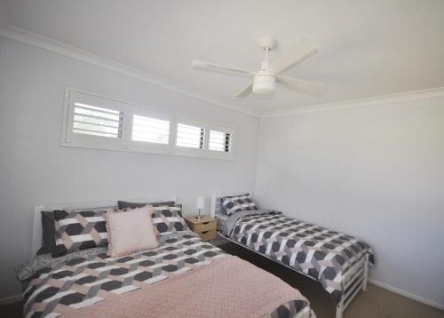 a bedroom with two beds and a ceiling fan at Island Time in Bongaree