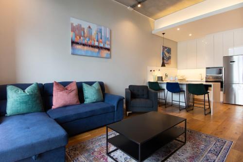 a living room with a blue couch and a kitchen at Urban Elephant. The Docklands in Cape Town