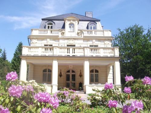 uma casa branca com varanda e flores roxas em Villa Bleichröder em Heringsdorf