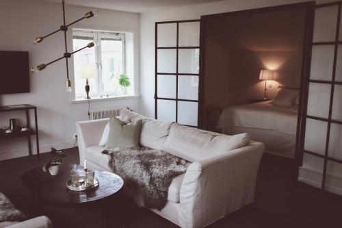 a living room with a white couch and a bed at Hotell Villa Borgen in Visby