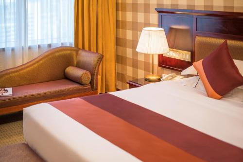 a hotel room with a bed and a chair at Asia International Hotel Guangdong in Guangzhou