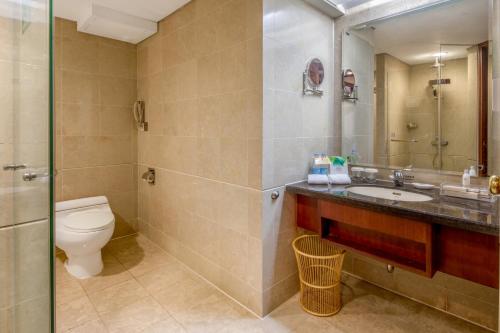 a bathroom with a toilet and a sink and a mirror at Asia International Hotel Guangdong in Guangzhou