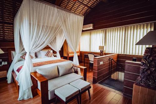 - une chambre avec un lit à baldaquin et une chaise dans l'établissement Tanamas Villas Ubud by Best Deals Asia Hospitality, à Ubud