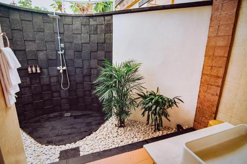 La salle de bains est pourvue d'une douche avec 2 plantes. dans l'établissement Tanamas Villas Ubud by Best Deals Asia Hospitality, à Ubud