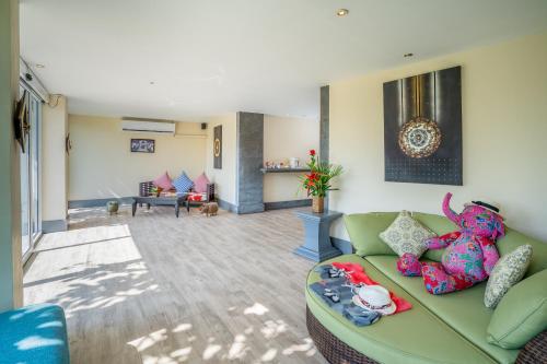 a living room with a green couch with a stuffed animal at The Briza Beach Resort, Samui - SHA Plus in Chaweng