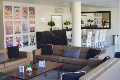 a living room with couches and a table and chairs at Cosmopolitan Hotel and Apartments in Melbourne