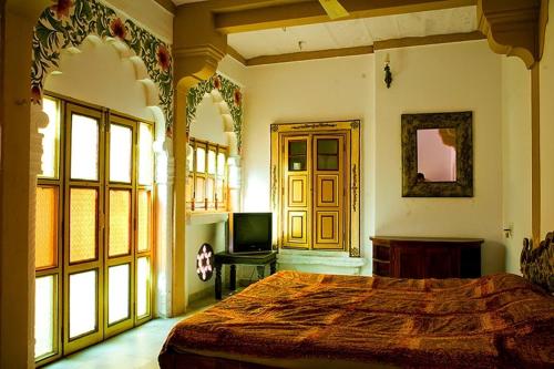 een slaapkamer met een bed en een televisie. bij Krishna Prakash Heritage Haveli in Jodhpur