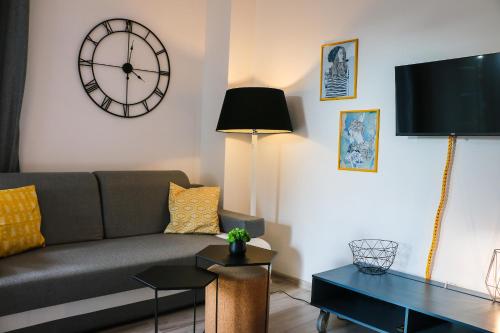 ein Wohnzimmer mit einer Couch und einer Uhr an der Wand in der Unterkunft Apartamenty Bryza-Matejki 1B-Parking in Świnoujście