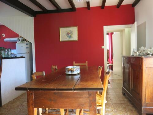 a dining room with a wooden table and a red wall at Au Relais de Nèche. in Bègues