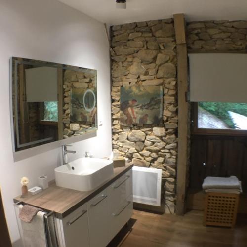 une salle de bain avec un lavabo et un mur en pierre dans l'établissement Le Gîte du Château de Durfort, à Soursac