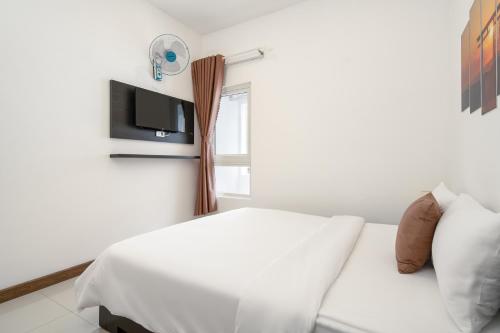 a white bedroom with a bed and a tv at Phuong Dong Hotel and Apartment in Quy Nhon